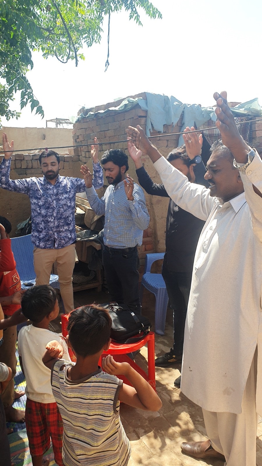 Men worshipping with raised hands outdoors in Pakistan