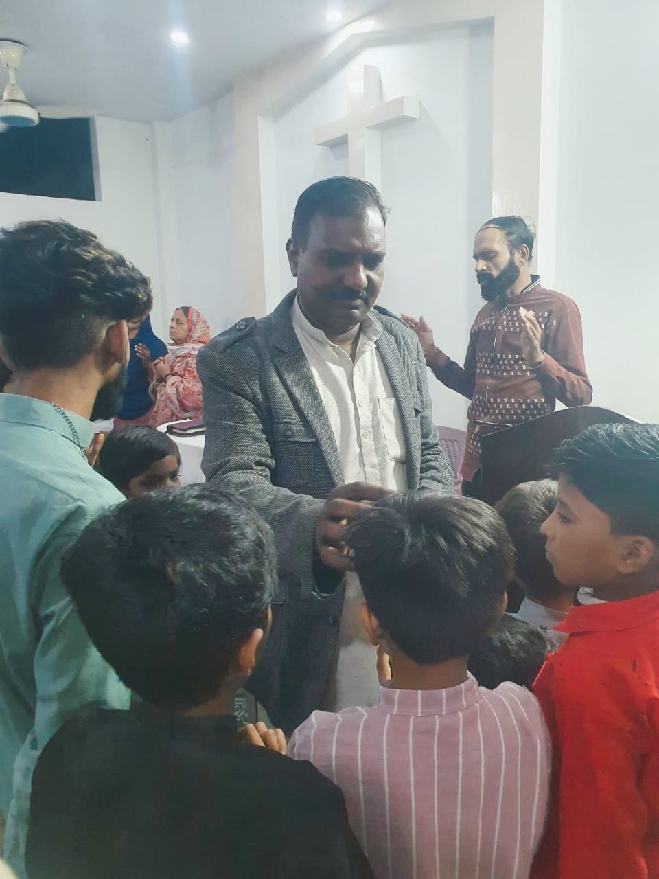 Pastor praying with children inside a church in Pakistan
