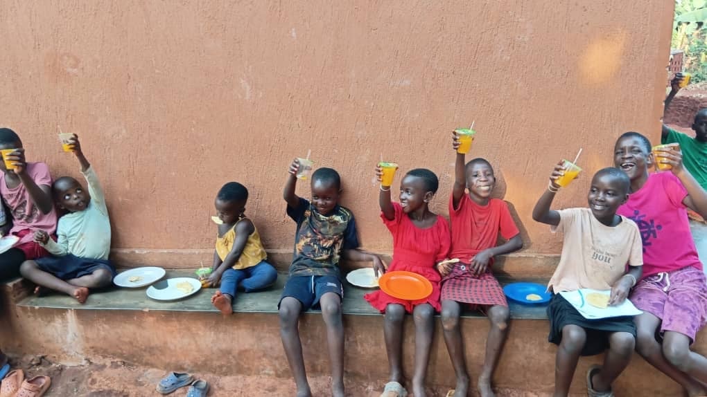 Children celebrating and raising their cups in Uganda